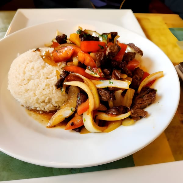 Peruvian Lomo Saltado with beef, onions, tomatoes, and rice on a white plate at Viva restaurant.