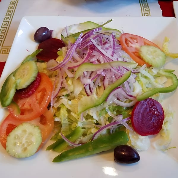 Peruvian side salad with lettuce, tomatoes, cucumbers, red onions, green peppers, beets, and olives.
