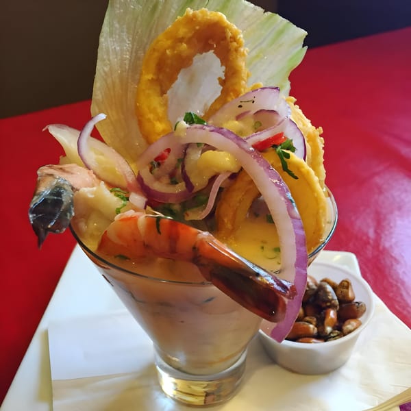 Peruvian ceviche with shrimp, calamari, red onions, and lettuce in a glass, with toasted corn.